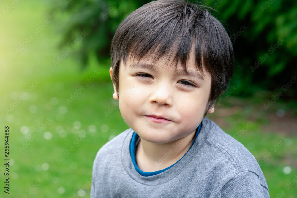 Head shot of happy kid sitting in the park with bright light sunny day, Portrait child playing outdoor in summer with blurry green natural park background, Positive children concept Head shot of happy kid sitting in the park with bright light sunny day, Portrait child playing outdoor in summer with blurry green natural park background, Positive children concept