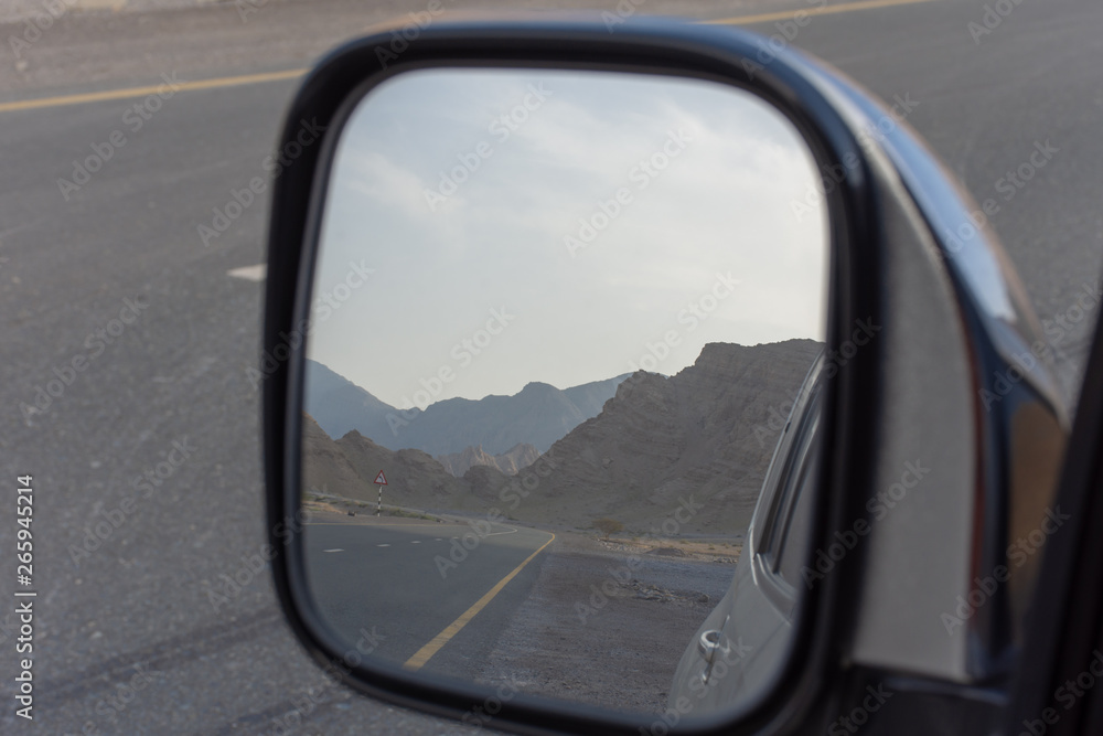 Reflection in rear view side mirror of road while driving along Jebal Jais Mountain road in Ras al Khaimah, United Arab Emirates (UAE)