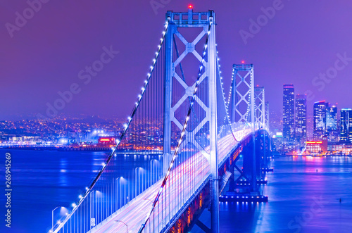 View of Bay Bridge across San Francisco Bay with lots of cars passing through in San Francisco at night.