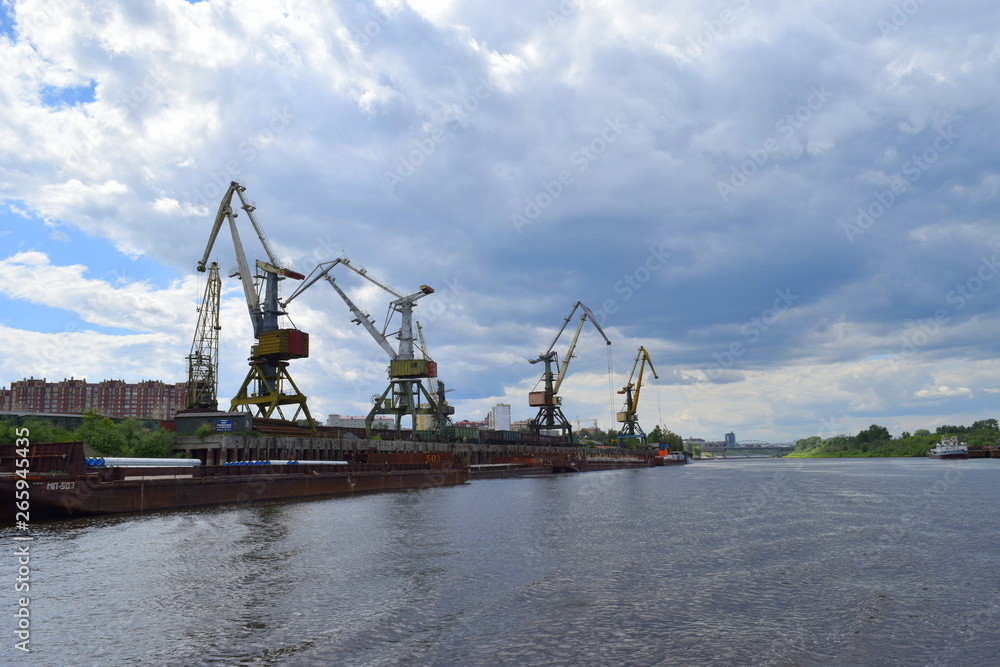 Port cranes on the river Tura. Tyumen river port. Russia Siberia. Port cranes on the river Tura. Tyumen river port. Russia Siberia.