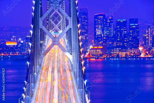 View of Bay Bridge across San Francisco Bay with lots of cars passing through in San Francisco at night.