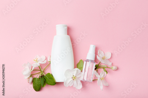 Face care products  tonic or lotion  serum  spray  micellar water  on pink background with spring apple blossom. Freshness natural anti-age care. Female everyday fresh cosmetics