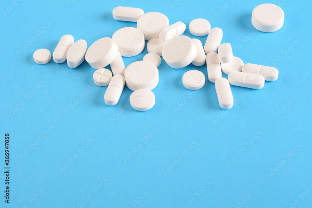 Pile of white pills on light blue background Pile of white pills on light blue background