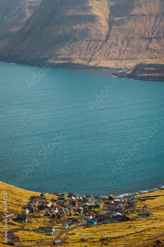 The small village of Funningur as seen from above with huge mountains and turquoise sea as a stunning background enlighted with sun (Faroe Islands, Denmark, Europe) photo