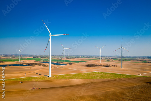 Aerial view of wind turbines in spring on brown field