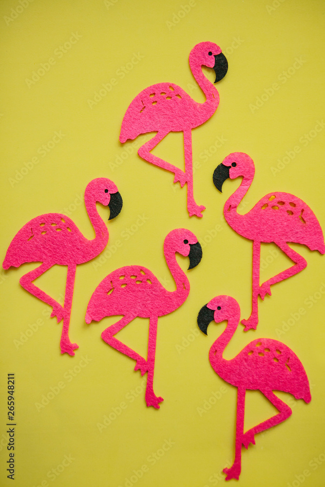 Many felt pink flamingos on a yellow background. Summer design.