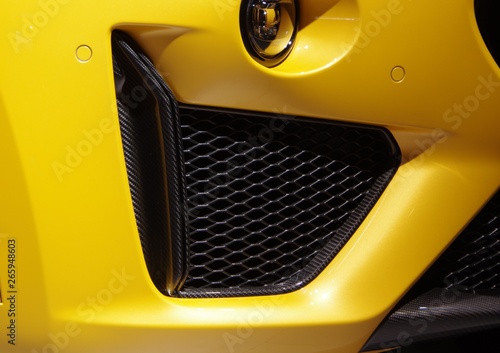 Yellow modern SUV car front air inlet grille and carbon fiber components detail photo