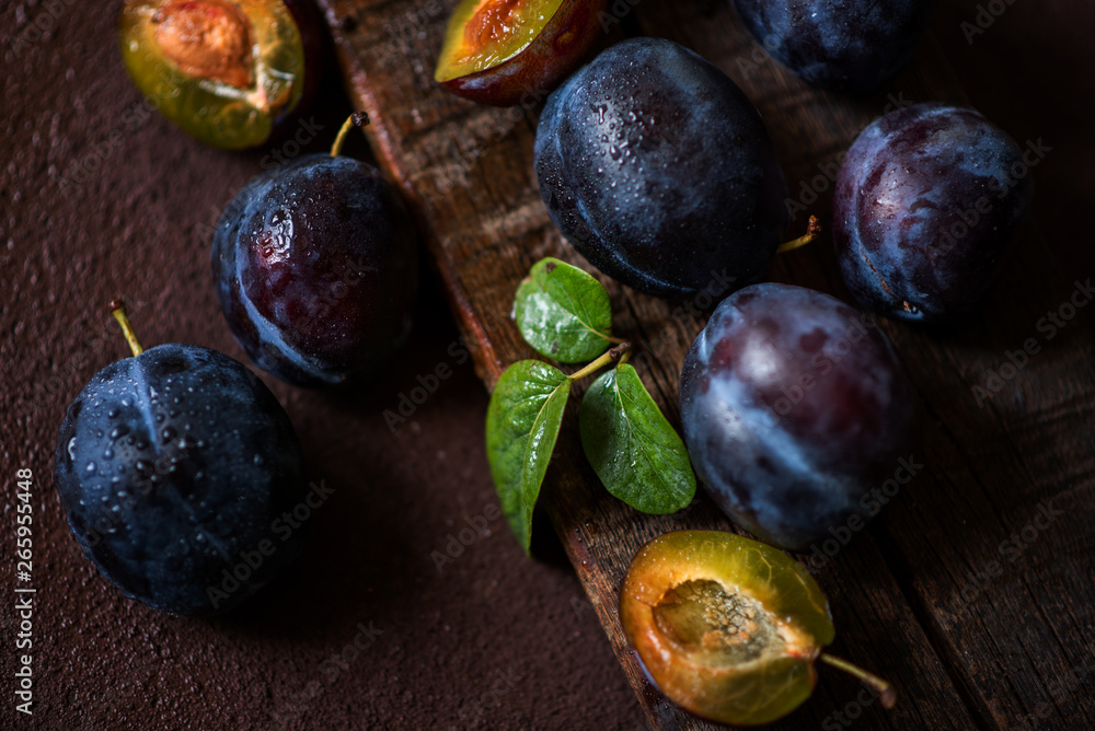 Plums in drops on a dark wood background. Toning. Selective focus. Plums in drops on a dark wood background. Toning. Selective focus.