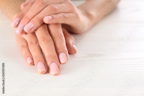 Closeup view of woman with beautiful hands at white wooden table  space for text. Spa treatment