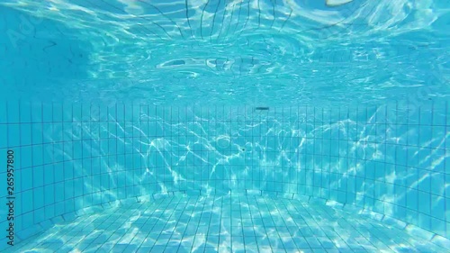 Wave texture on the bottom of swimming pool and sun rays