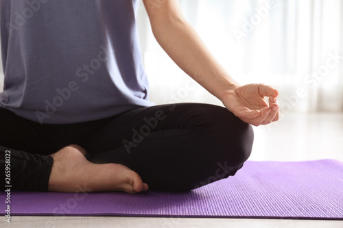 Woman practicing yoga on floor indoors, closeup