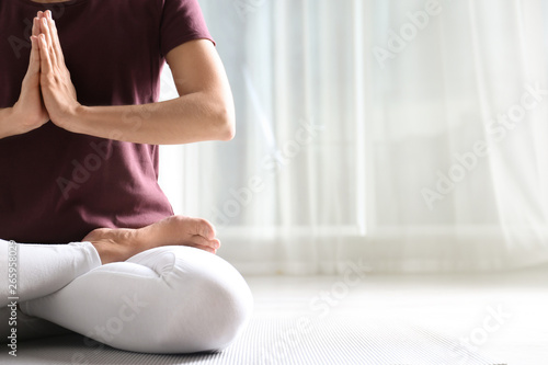 Woman practicing yoga on floor indoors, closeup. Space for text