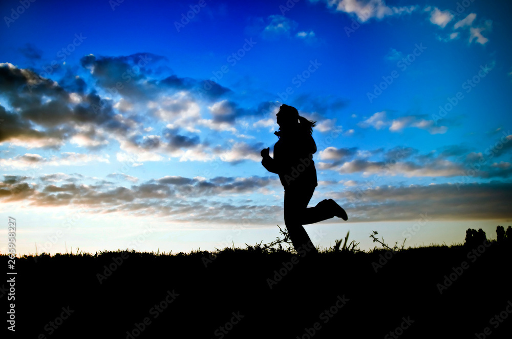 Running woman - jogger woman - in nature over sunset sky like sport, hobby and fitness concept 