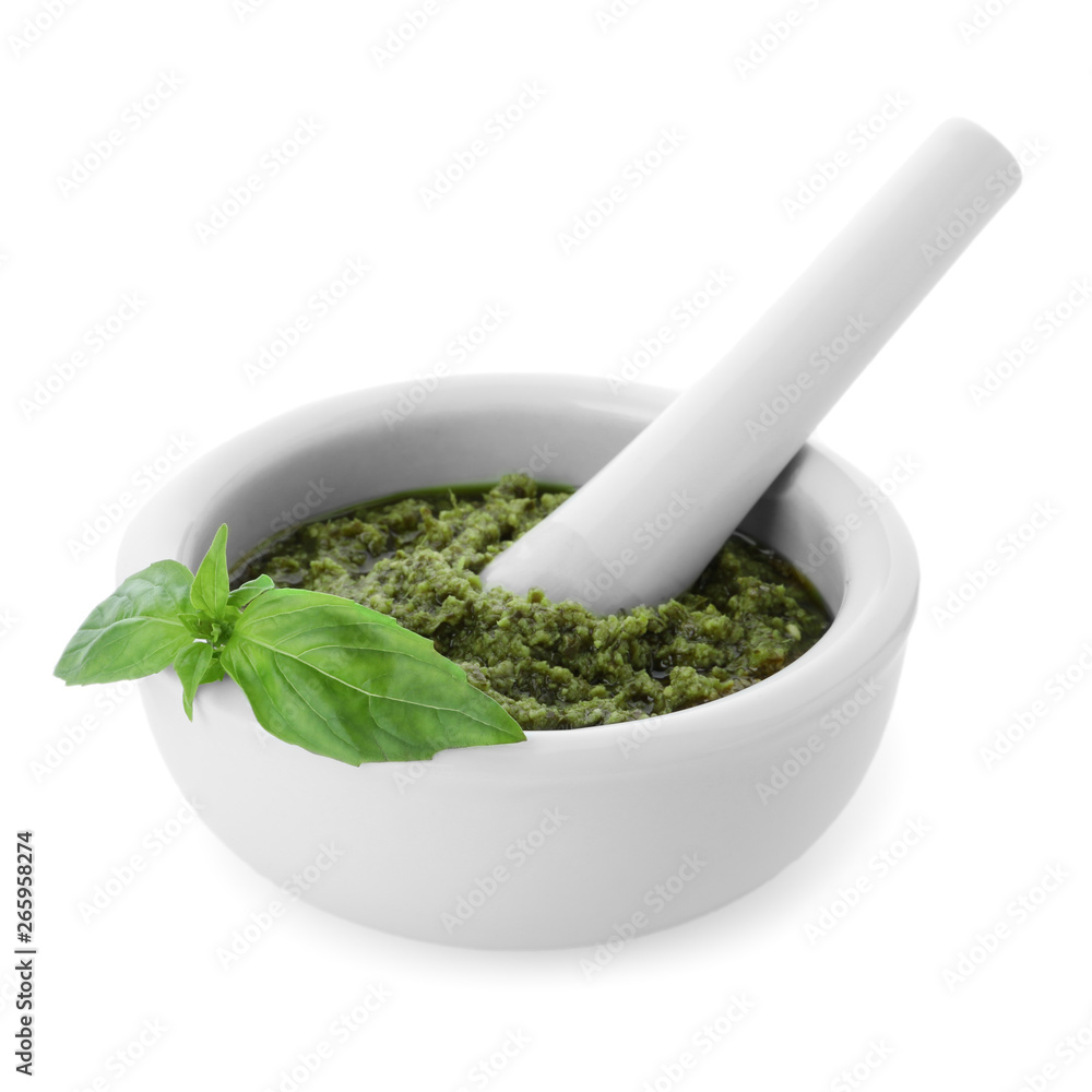 Mortar of tasty pesto sauce with basil leaves and pestle isolated on white