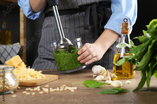 Photos Woman blending pesto sauce in bowl at table, closeup