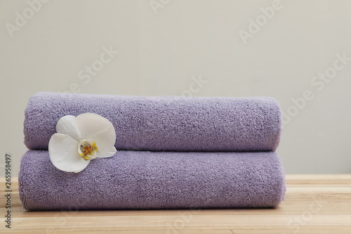Stack of fresh towels with flower on table