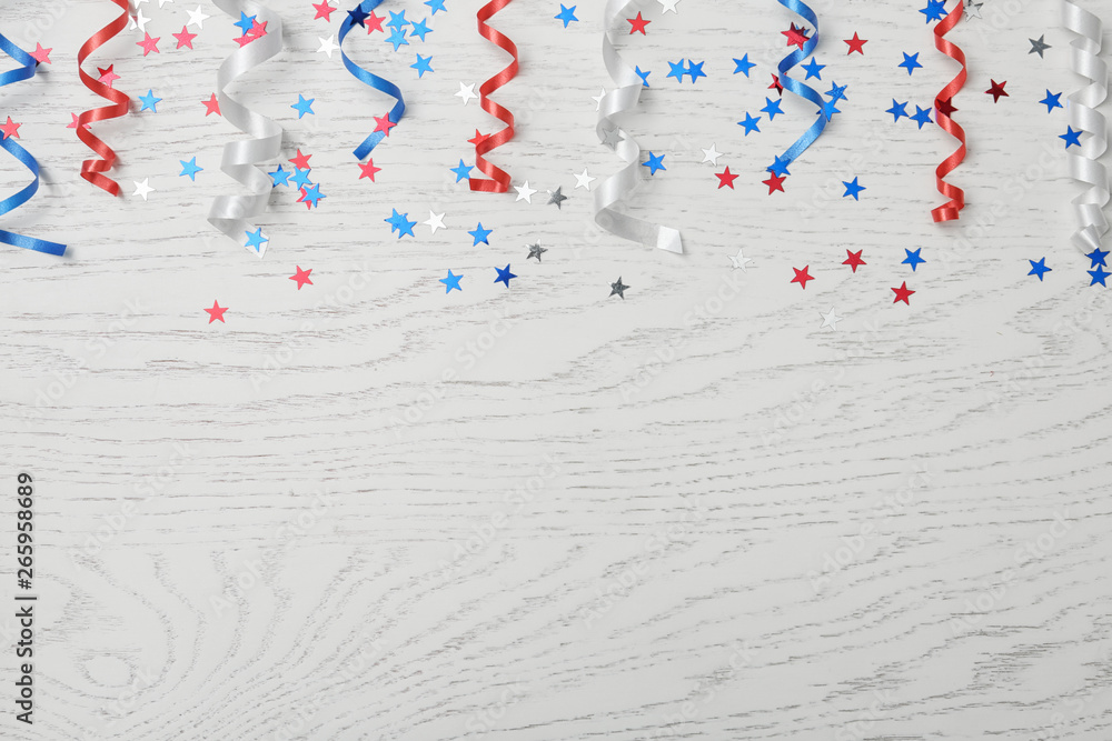 Fototapeta premium Flat lay composition with colorful party streamers on wooden table, space for text. USA Independence Day
