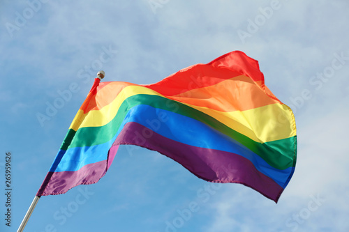 Bright rainbow gay flag fluttering against blue sky. LGBT community photo