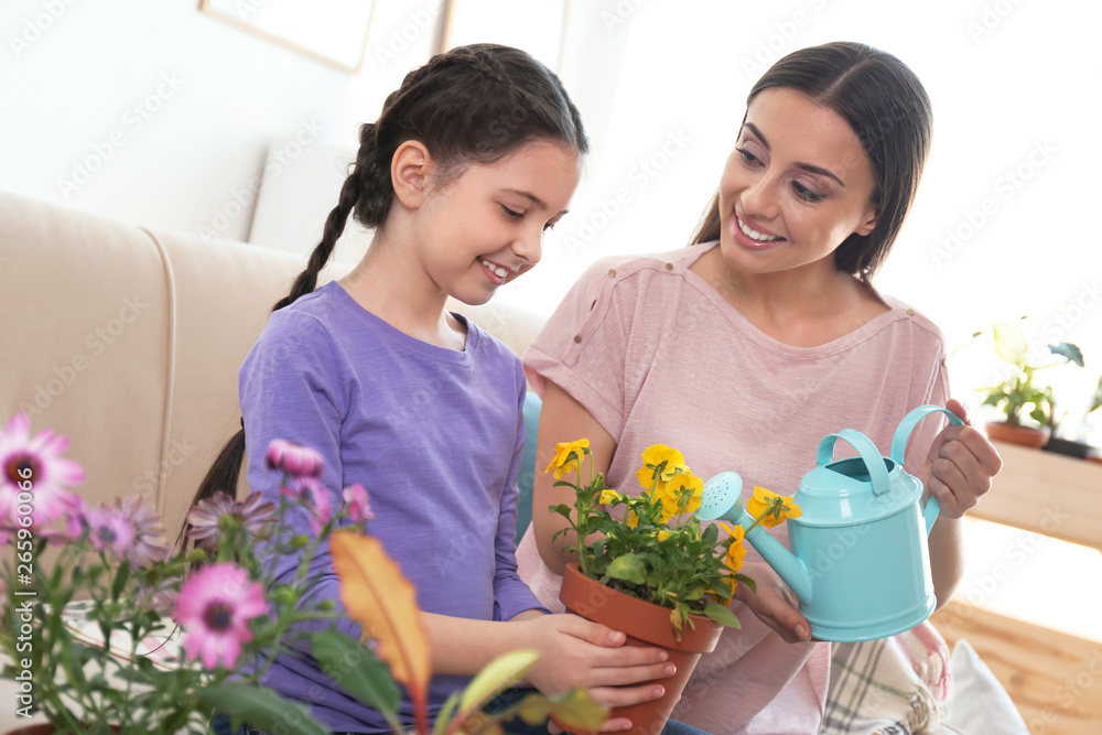 Mother and daughter watering potted plants at home