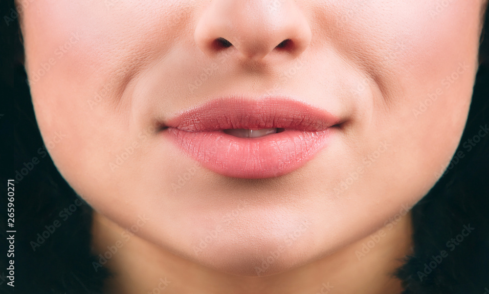 Obraz premium Close up of nice young woman's lips smiling a bit. Short black hair. Healthy skin. Cut view.