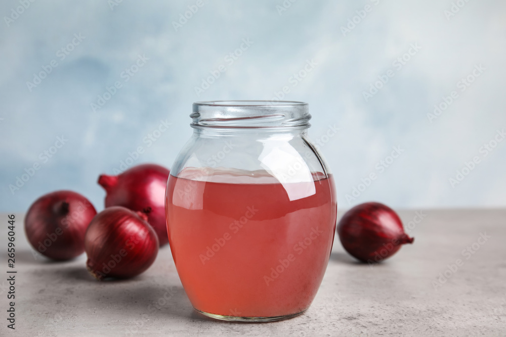 Glass jar of onion syrup and fresh vegetable on table Glass jar of onion syrup and fresh vegetable on table