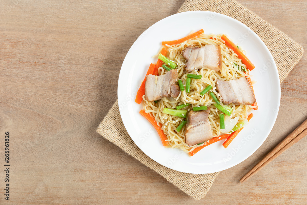 top view of stir fried egg noodles with pork belly in a ceramic dish on wooden table. asian homemade style food concept. top view of stir fried egg noodles with pork belly in a ceramic dish on wooden table. asian homemade style food concept.