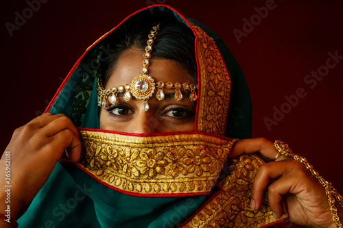 Woman lighting diyas with nuth nath nose piercing and the golden teak with traditionak fashion sari photo