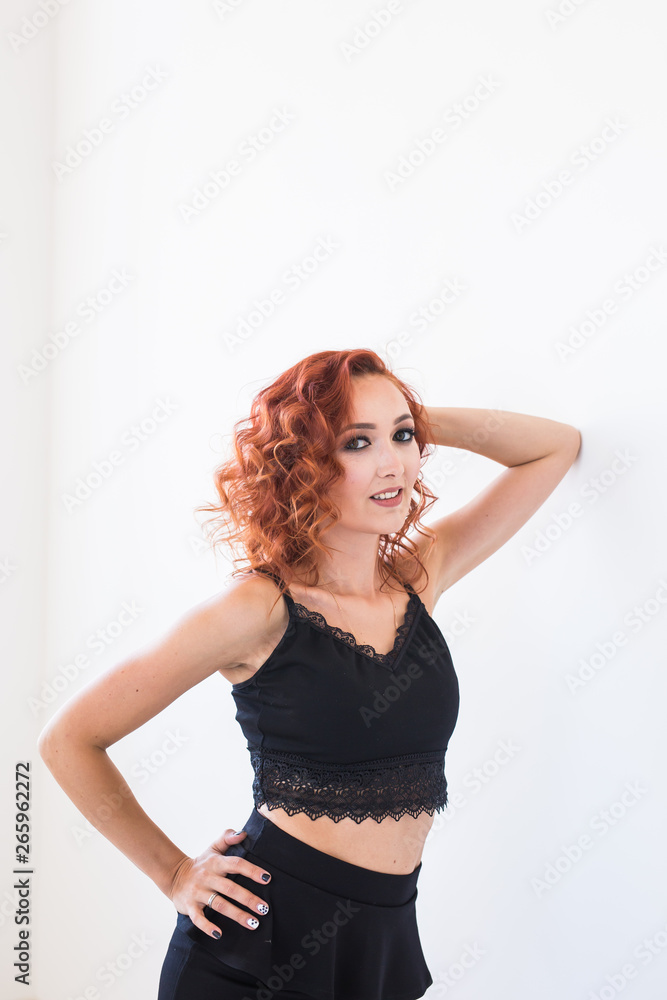 People and fashion concept - Redhead model posing over white wall background People and fashion concept - Redhead model posing over white wall background