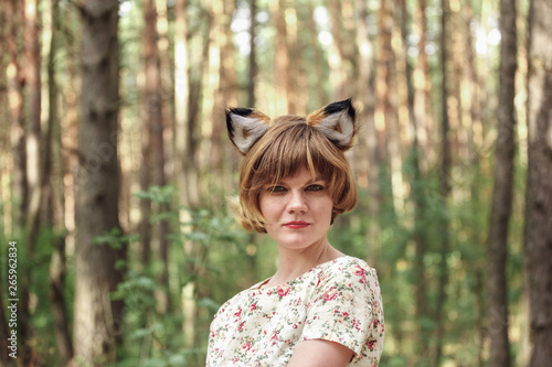 Young woman with fox ears against the background of a pine forest