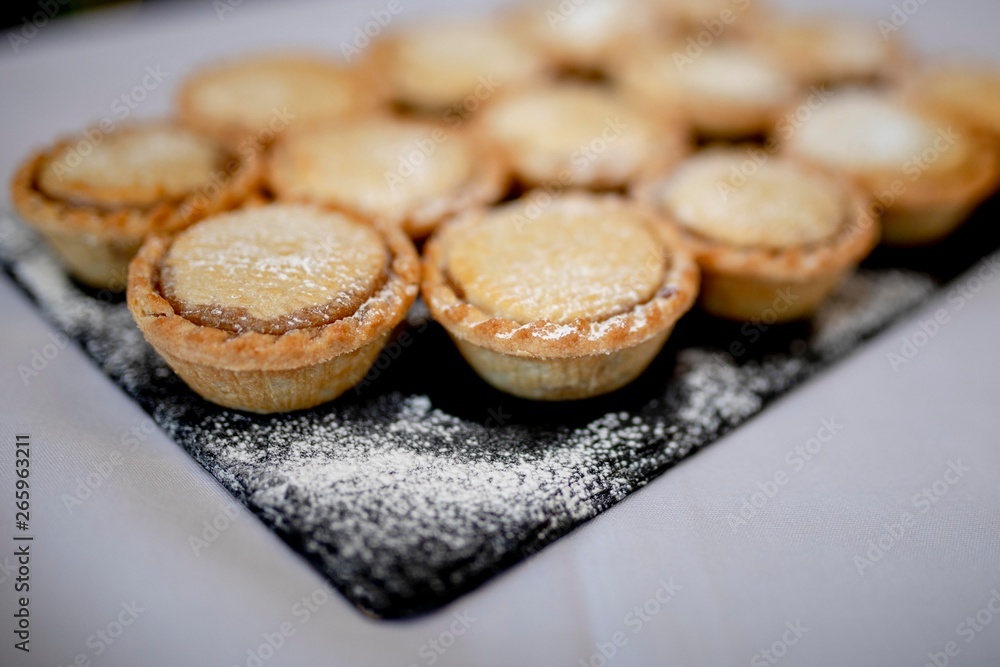 Close up delicious home baked seasonal frosted Christmas mince pies on slate plate on a buffet in a luxury hotel