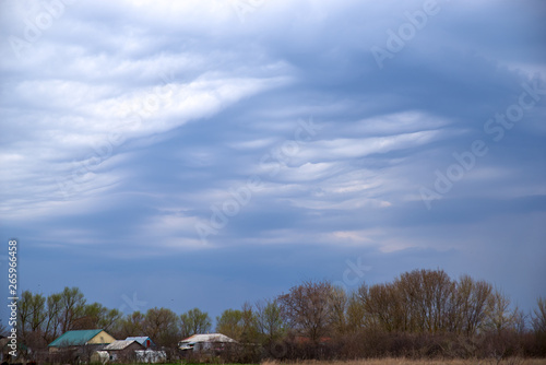 Rural landscape in dark colours with a dark ominous sky. Wavy low heavy clouds and sky