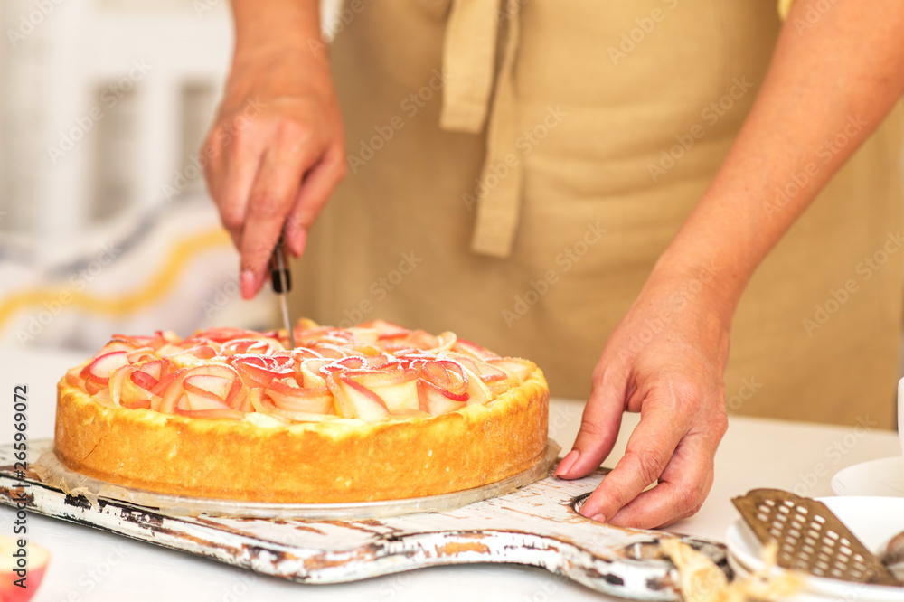 Sweet homemade pie ready to eating. Whole apple pie and a piece is taken out with a cake server. Tasty apple cake served for dessert. Traditional apple pie with cinnamon.