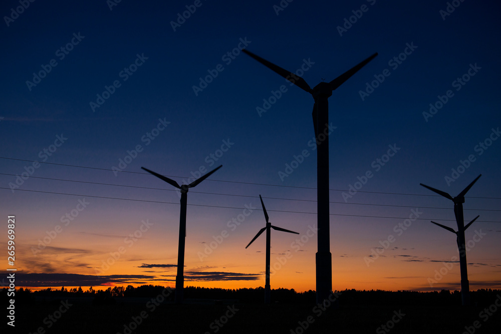 Power generators of windmills at shadow sunset - Wind turbine on field at sunset Power generators of windmills at shadow sunset - Wind turbine on field at sunset