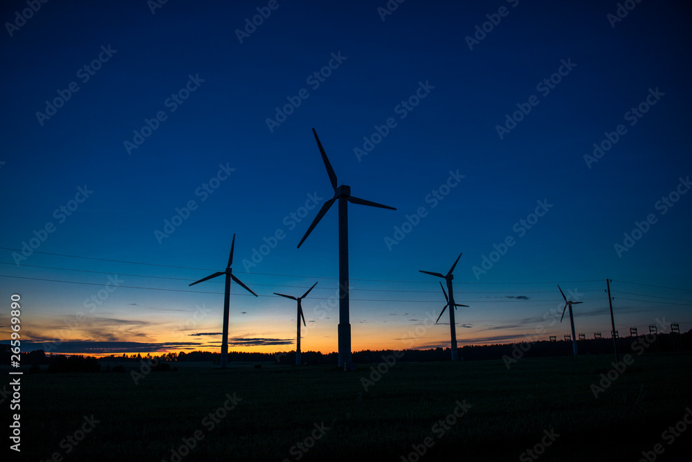 Obraz premium Power generators of windmills at shadow sunset - Wind turbine on field at sunset