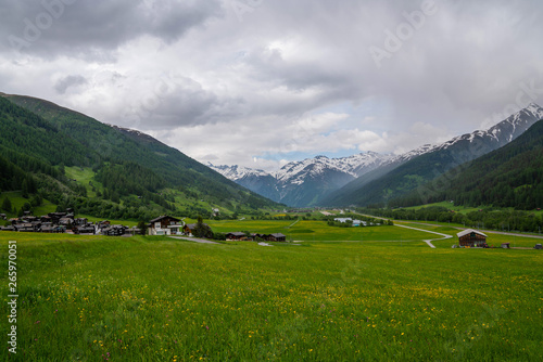 Picturesque village withg green meadow and old historic mountain chaletes in the Swiss Alps. Lush green grass and meadow flowers. Old historic chaletes in mountain village on the background.