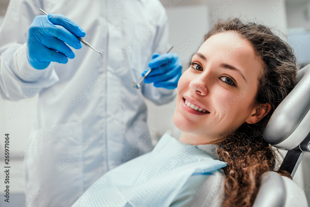 © HBS - Smiling young woman receiving dental checkup. close up view. Healthcare and medicine concept.