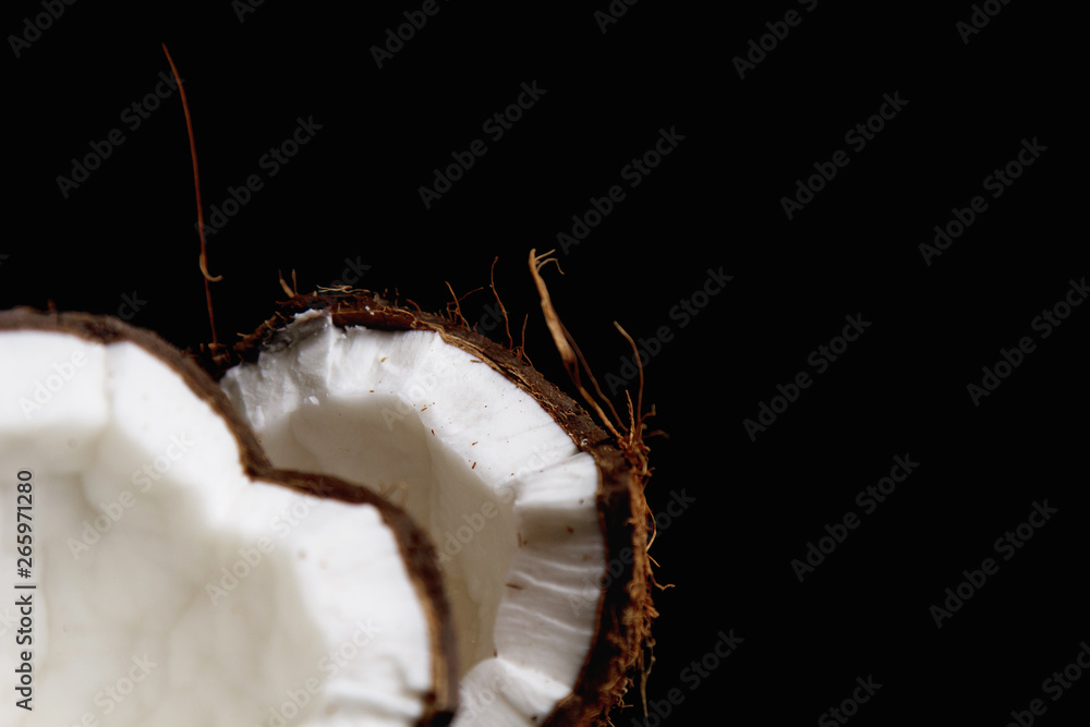 ripe coconut is broken into two halves isolated on a black background close-up. the insides of the tropical palm fetus ripe coconut is broken into two halves isolated on a black background close-up. the insides of the tropical palm fetus