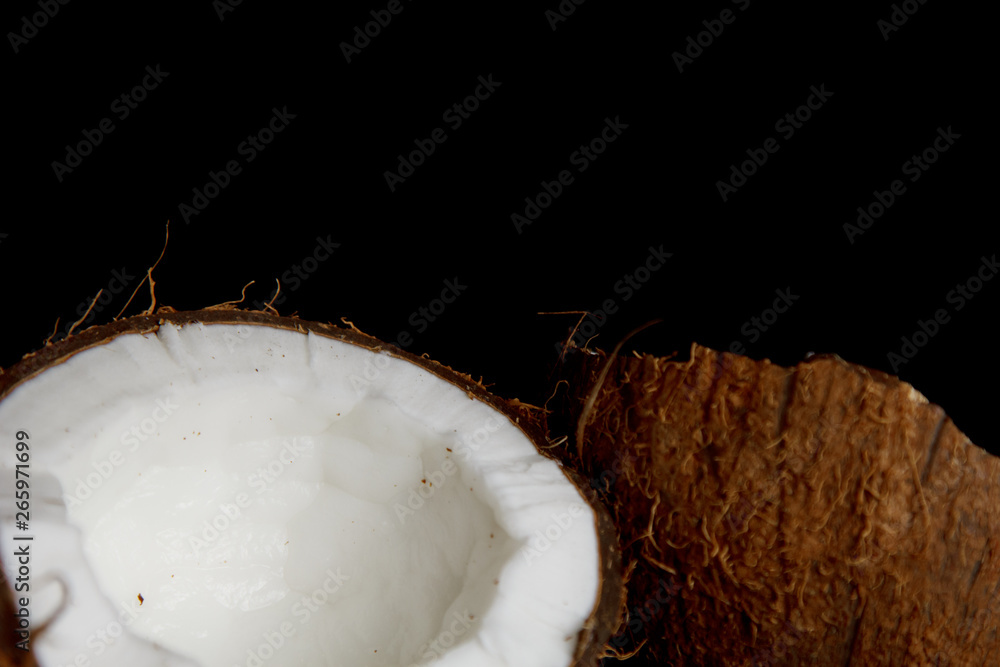 ripe coconut is broken into two halves isolated on a black background close-up. the insides of the tropical palm fetus ripe coconut is broken into two halves isolated on a black background close-up. the insides of the tropical palm fetus