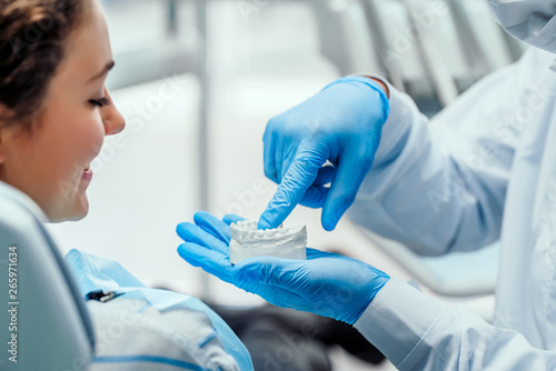 Dentist explaining the details of dental mold to his patient. Close up view. photo