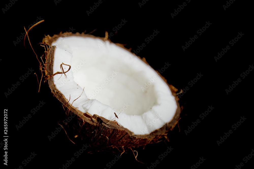ripe coconut is broken into two halves isolated on a black background close-up. the insides of the tropical palm fetus ripe coconut is broken into two halves isolated on a black background close-up. the insides of the tropical palm fetus