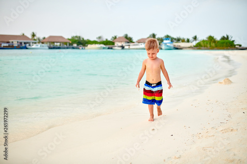 Three year old toddler boy on beach at sunset
