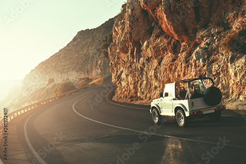 SUV car driving along empty country road at golden summer sunset. People traveling, road trip on lycian way through beautiful mountains coast scenery in sunny summer. Happy journey concept photo