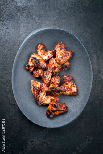 Traditional barbecue chicken wings with hot chili sauce as top view gray modern design bowl with copy space