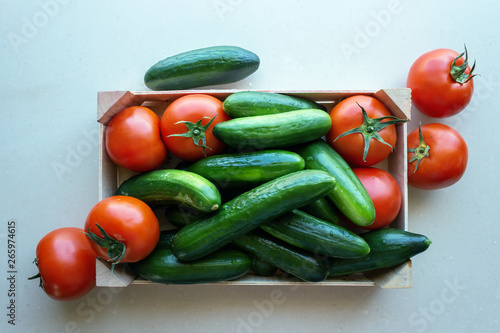 Tomatoes and cucumbers in a wooden crate. Concept- fresh organic vegetables, healthy food from garden.