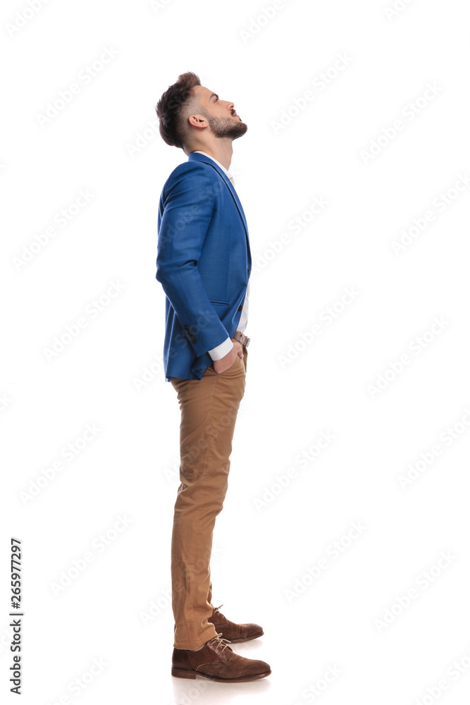 Fototapeta premium handsome man standing with hands in pockets while looking up
