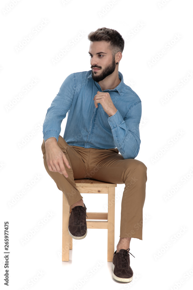 relaxed man sitting with elbow on leg while looking away relaxed man sitting with elbow on leg while looking away