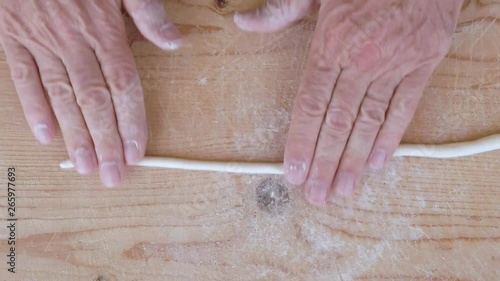 Mani di un uomo stanno stendendo la pasta filata fatta in casa su un tagliere di legno. photo