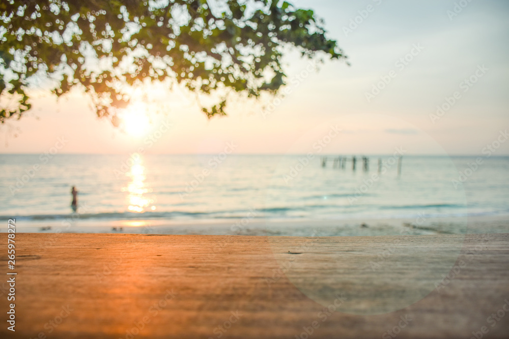 wooden desk with flare of sunset on blurred sea and bokeh branch foreground. wooden desk with flare of sunset on blurred sea and bokeh branch foreground.