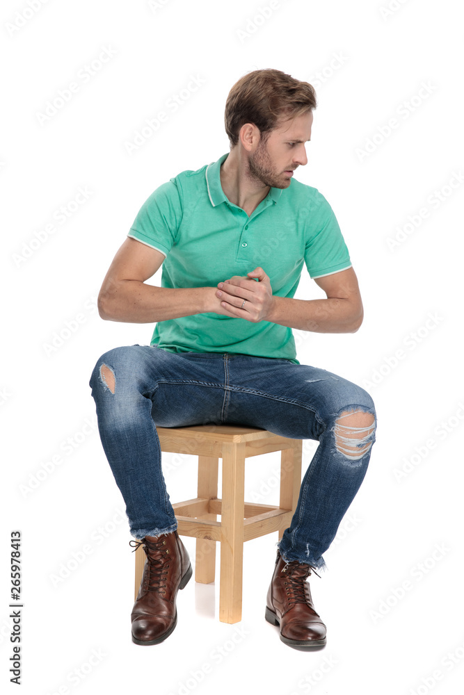 seated displeased man threatening with his fists while looking away