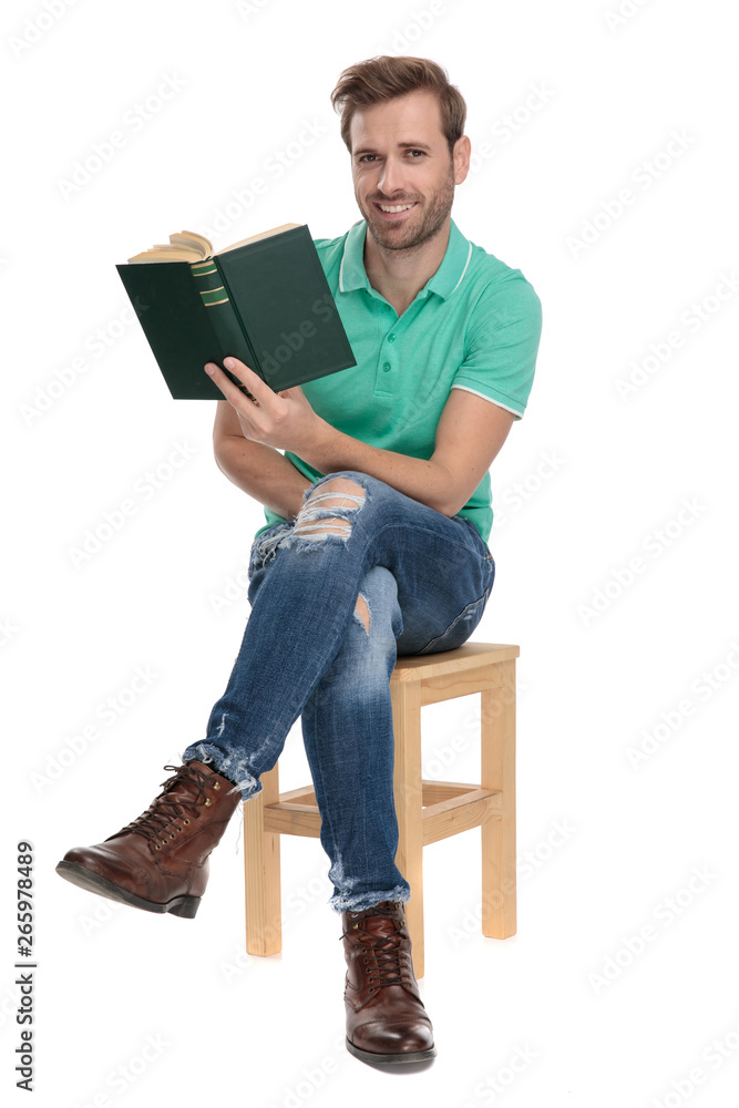 seated happy man holding book in hand with legs crossed seated happy man holding book in hand with legs crossed